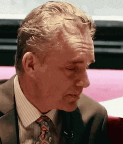 Man In Suit And Tie Sitting At Pink Table GIF