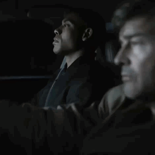 Man In Suit And Tie Sitting In Dark Room GIF