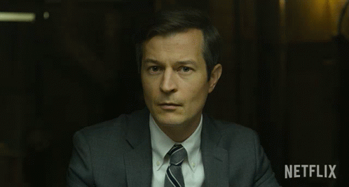 Man in Suit and Tie Sitting in Front of Netflix Sign
