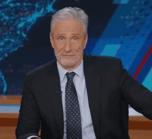 Man In Suit And Tie Sitting In Front Of Screen GIF