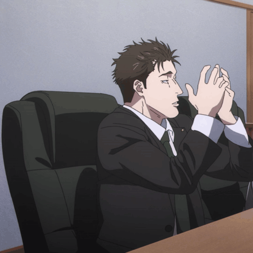 Man in Suit and Tie Sitting with Hands Folded