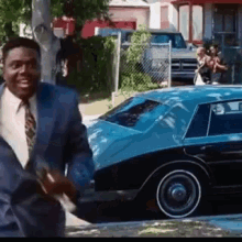 Man in Suit and Tie Smiling by Blue Car