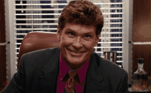 Man in Suit and Tie Smiling in Front of Window