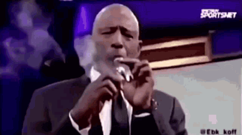 Man In Suit And Tie Smoking Cigarette And Speaking Into Microphone GIF