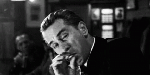 Man in Suit and Tie Smoking Cigarette in Bar