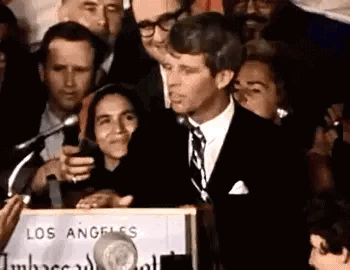 Man in Suit and Tie Speaking at Podium