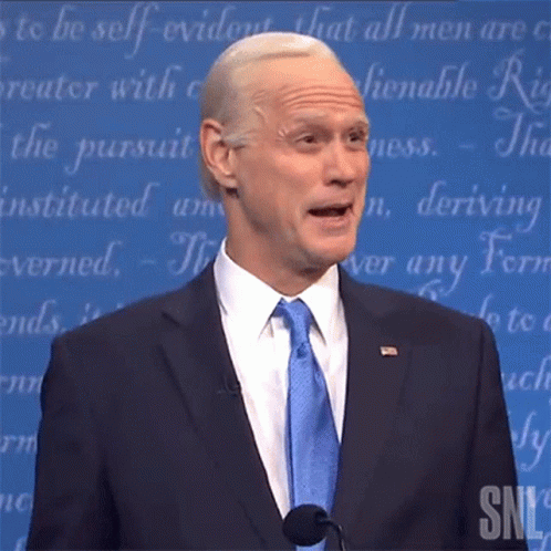 Man in Suit and Tie Speaking Microphone SNL Logo