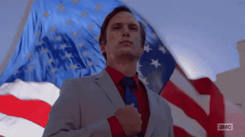 Man in Suit and Tie Standing Before American Flag
