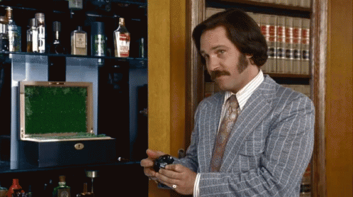 Man in Suit and Tie Standing Before Bookshelf