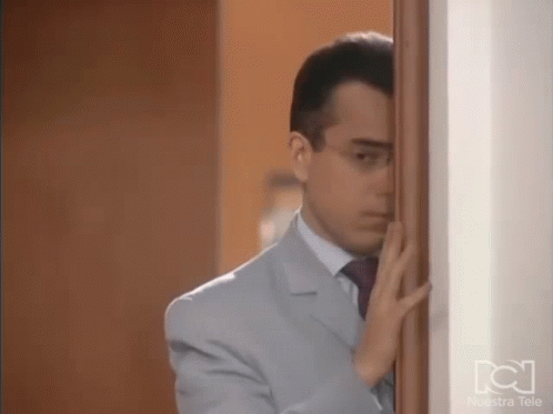 Man in Suit and Tie Standing Behind Door