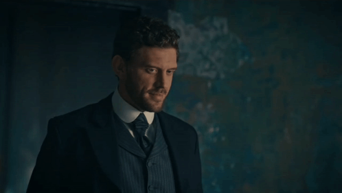 Man In Suit And Tie Standing In Dark Room GIF