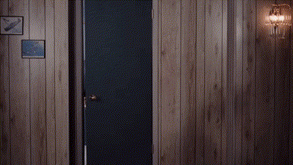 Man in Suit and Tie Standing in Doorway in Wood Paneled Room