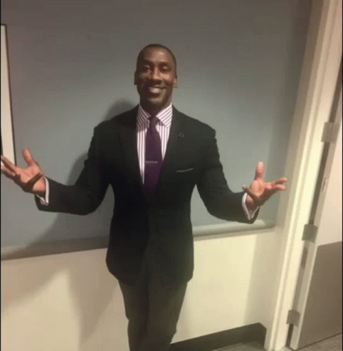 Man in Suit and Tie Standing in Doorway With Arms Outstretched