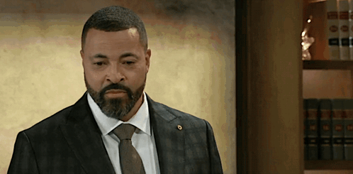 Man In Suit And Tie Standing In Front Of Bookshelf GIF