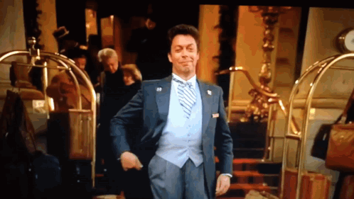 Man in Suit and Tie Standing in Front of Hotel