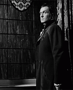 Man in Suit and Tie Standing in Front of Window Black and White