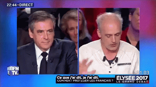 Man In Suit And Tie Talking To Another Man On TV Show GIF