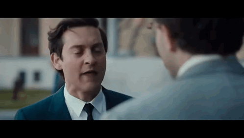 Man in Suit and Tie Talking to Man in White Shirt