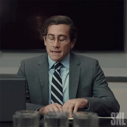 Man In Suit And Tie Typing On Laptop With SNL Logo GIF