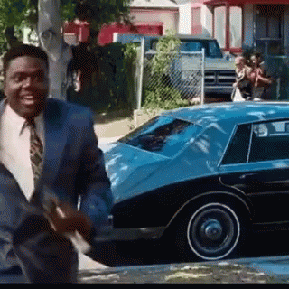 Man in Suit and Tie Walking in Front of Blue Car