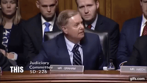 Man In Suit And Tie With Sign Saying This GIF