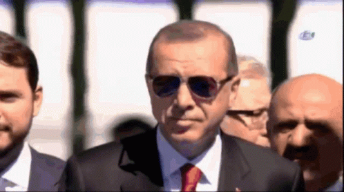 Man in Suit and Tie With Sunglasses Before Group