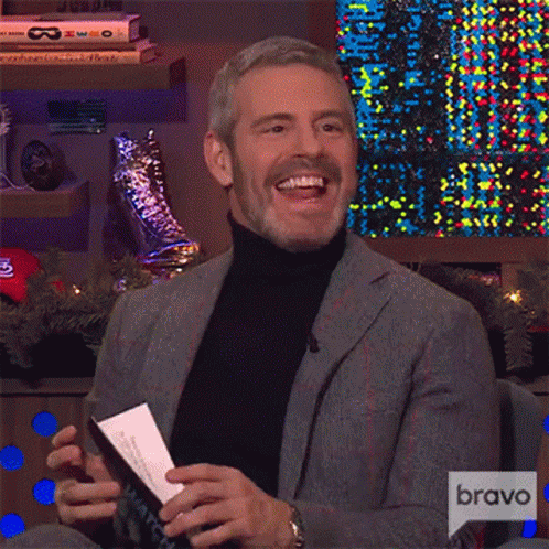 Man in Suit and Turtleneck Laughing Holding Paper