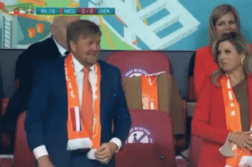 Man in Suit and Woman in Red Jacket at Stadium