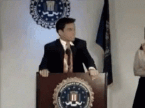 Man in Suit at Podium with DOJ Seal