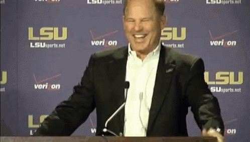 Man in Suit at Podium with LSU Sign