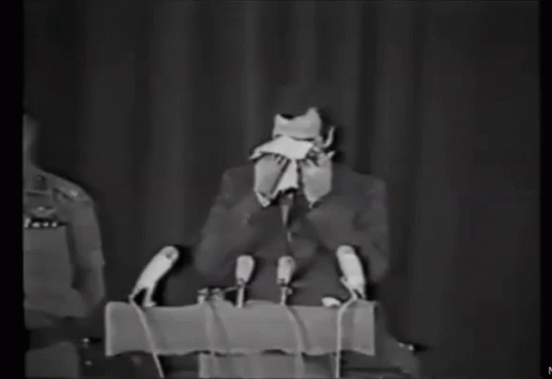 Man in Suit at Podium with Microphones