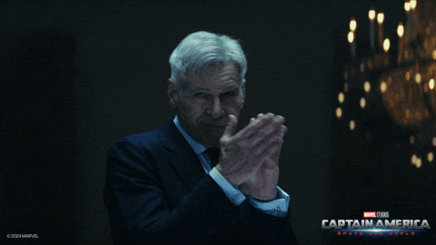 Man in Suit Clapping in Front of Captain America Poster