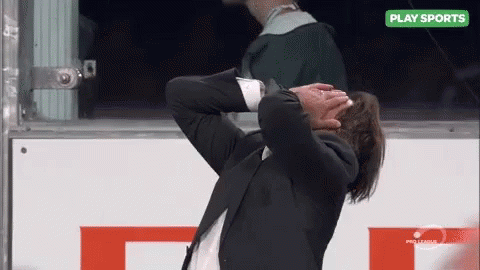 Man in Suit Covering Face at Sports Sign