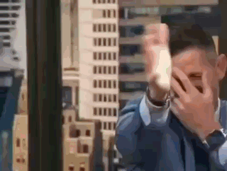Man in Suit Covering Face Before City Skyline