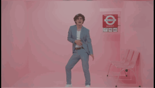 Man in Suit Dancing by Pink Wall I Need Your Love