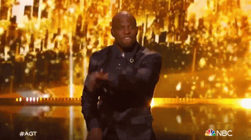 Man in Suit Dancing on Stage With NBC Logo