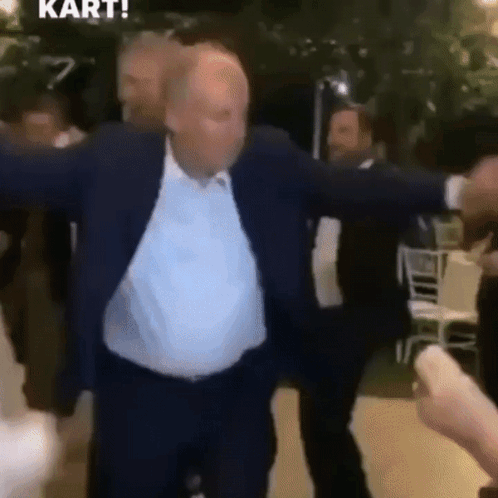 Man In Suit Dancing With Arms Outstretched In Crowd GIF