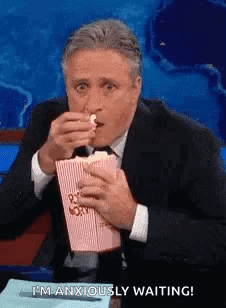 Man In Suit Eating Popcorn At Table GIF
