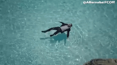 Man In Suit Floating On Back In Pool GIF