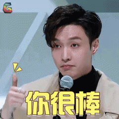 Man in Suit Giving Thumbs Up in Front of Microphone with Chinese Writing