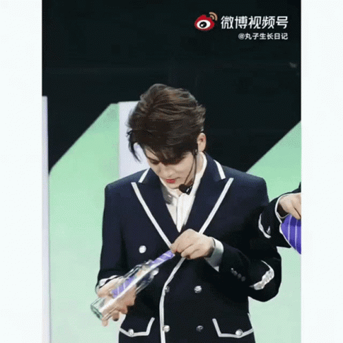 Man in Suit Holding Bottle With Chinese Writing
