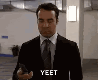 Man in Suit Holding Cell Phone Says Yeet