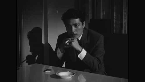 Man in Suit Holding Cigarette at Table