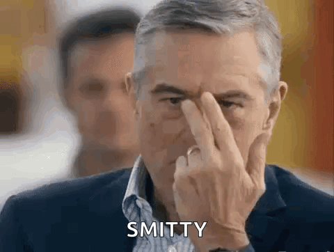 Man in Suit Holding Finger to Forehead Saying Smitten