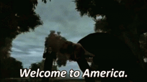 Man in Suit Holding Gun Welcome to America
