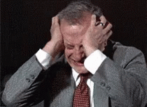 Man in Suit Holding Head in Pain