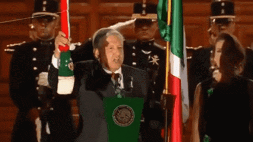 Man in Suit Holding Mexican Flag at Podium