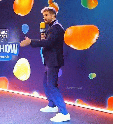 Man in Suit Holding Microphone Saying How Music