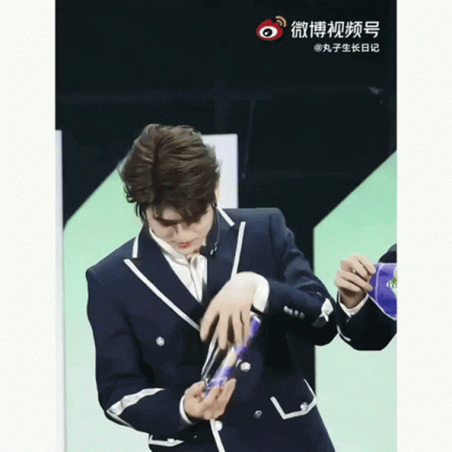 Man in Suit Holding Object With Chinese Writing