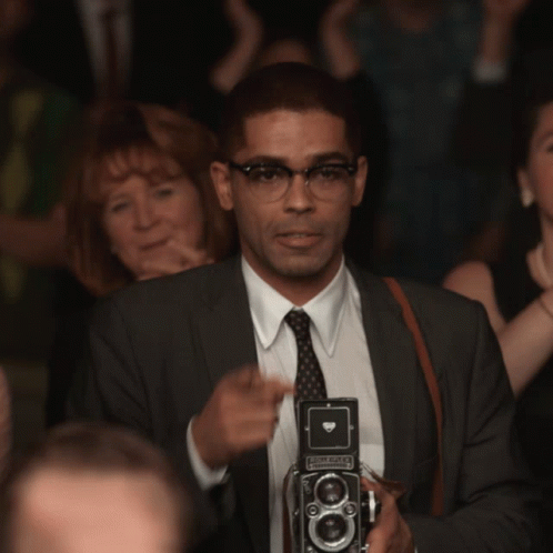 Man In Suit Holding Olympus Camera GIF